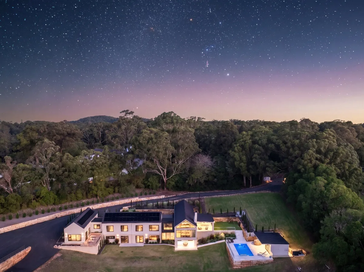 Elevated view of a modern home and swimming pool surrounded by trees at dusk